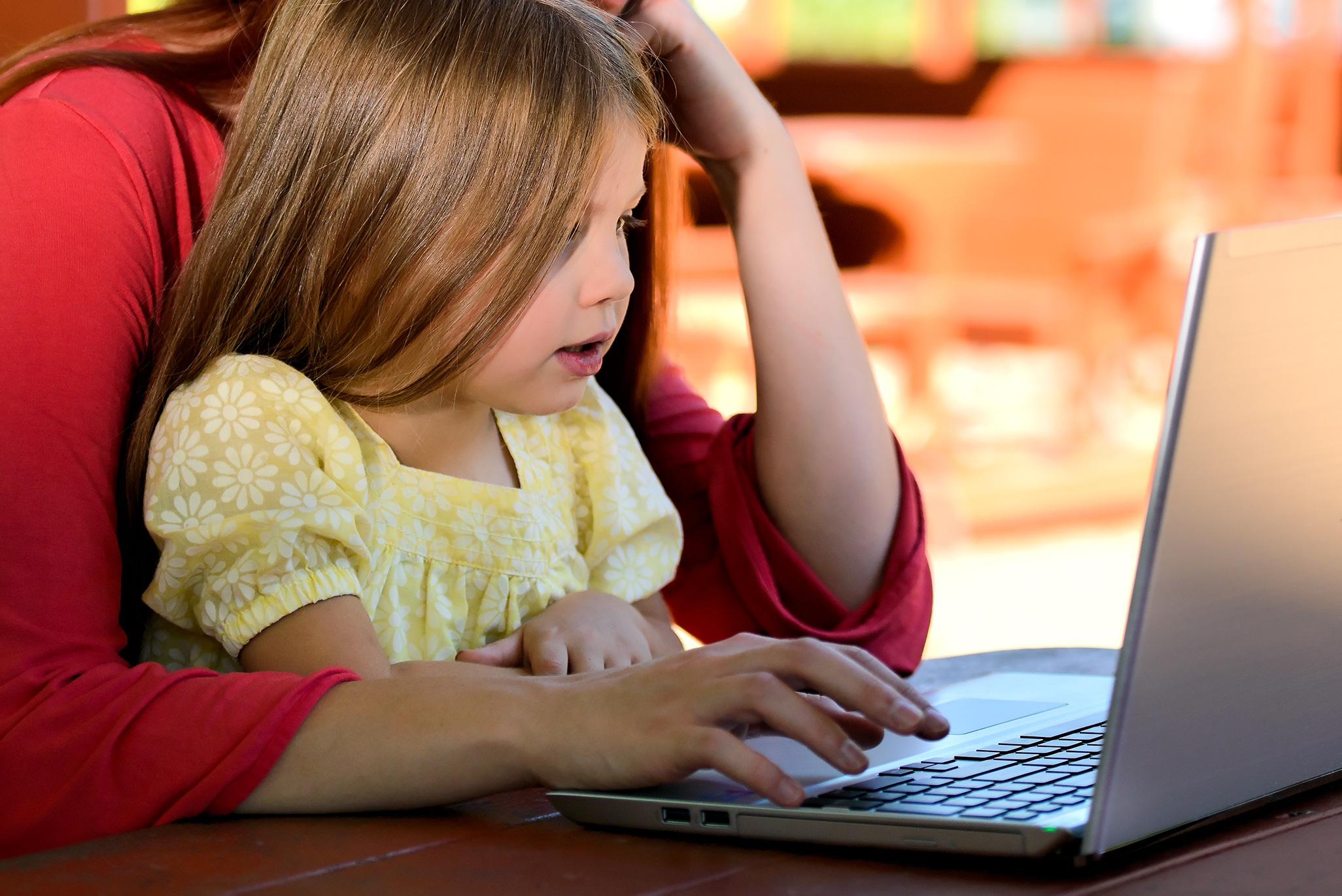 Canva - Brunette Woman in Red With Girl in Yellow on Lap Before Laptop (1)
